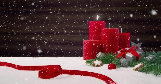 First Sunday of Advent - Beautiful snowfall in front of a Christmas decoration arrangement on a snowy table in front of a wooden background