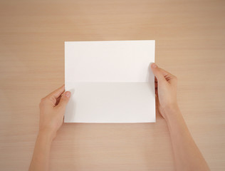 Obraz premium Hands holding blank white brochure booklet in the hand. Leaflet presentation. Pamphlet hand man. Show offset paper. Sheet template. Book in hands. Booklet folding design. Fold paper sheet display read