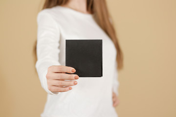 Girl showing blank black square flyer brochure booklet. Leaflet presentation. Pamphlet hold hands....