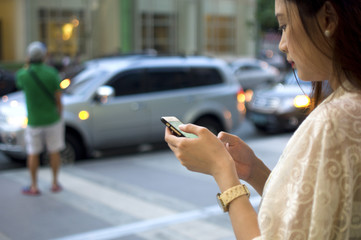A woman is waiting for a cab using her phone