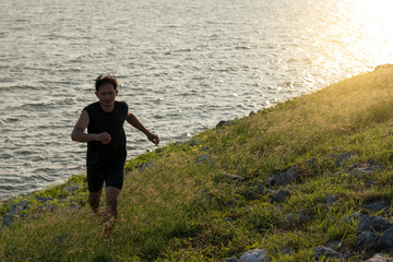 Fototapeta na wymiar Asia young man running in the nature in the time during sunrise on dam exercise. Healthy lifestyle