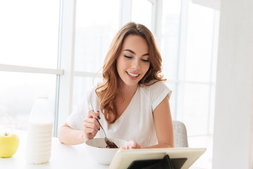 Obraz premium Beautiful young woman sitting at the kitchen near window