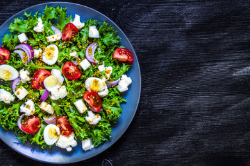 Salad of fresh vegetables on a black wooden background. View from above