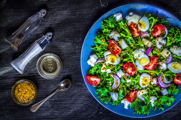 Salad of fresh vegetables on a black wooden background. View from above