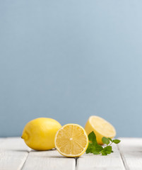 Ripe lemons and mint leaves on a white wooden table on a blue background..