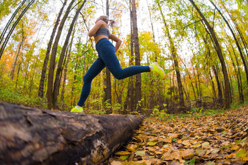 the girl jumps over a fallen tree in the forest