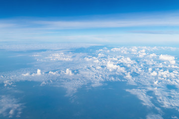 Fototapeta premium View from airplane window above the clouds with blue sky and cloudscape in sunlight morining. white wispy cirrus and cirrostratus clouds