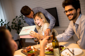 Happy smiling young woman receives gift from young man for New Year or Christmas