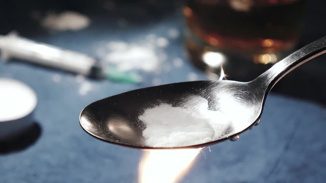 Cooking white heroin on a spoon, drug addiction
