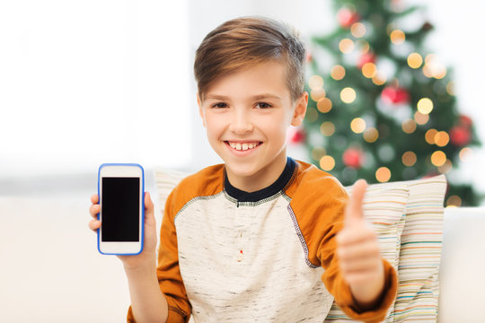 boy with smartphone at christmas showing thumbs up