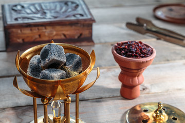 coals for Shisha Smoking are in the Golden bowl, made in the shape of a Lotus on the background of Smoking accessories