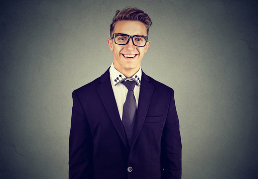 Laughing funny looking handsome businessman in glasses on gray wall background 