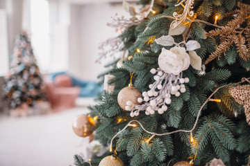 Original decor and toys hangs on rich Christmas tree standing in a cosy room