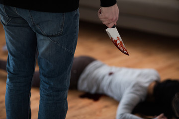 criminal with knife and dead body at crime scene