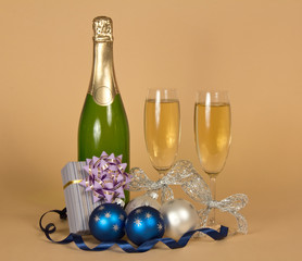 Bottle with champagne, gift box and Christmas decorations on beige
