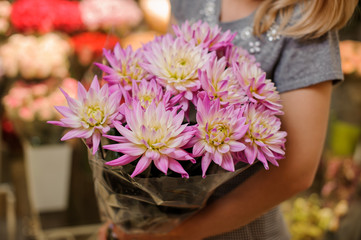 Florist in a grey dress holding a beautiful bright pink bouquet of flowers