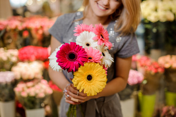 Naklejka premium Smiling florist in a grey dress holding a beautiful colorful bouquet of flowers