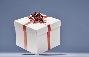 White cube gift box with red stripes and bow floating in intimate blue background