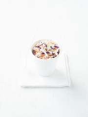 Portion of low-caloric vegetable coleslaw salad in a paper cup.