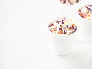 Portions of low-caloric vegetable coleslaw salad in a paper cups. Concept for healthy eating.