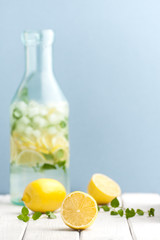 Ripe lemons and mint leaves against the background of a bottle of lemonade..