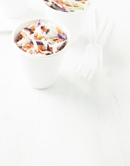 Portions of low-caloric vegetable coleslaw salad in a paper cups.