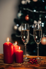 Two glasses of champagne on the background of a Christmas tree with candles with snow