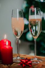 Two glasses of champagne on the background of a Christmas tree with candles with snow