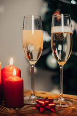 Two glasses of champagne on the background of a Christmas tree with candles with snow