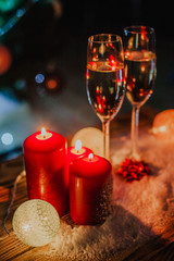 Two glasses of champagne on the background of a Christmas tree with candles in darkness with snow