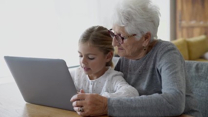 Little girl with grandmother using laptop computer - Powered by Adobe