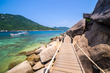 Naklejka premium A wooden footbridge at a rocky beach in thailand