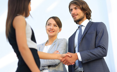 Businesspeople  shaking hands against room with large window loo