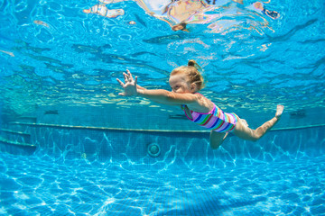 Funny portrait of child learn swimming, diving in blue pool with fun - jumping deep down underwater...