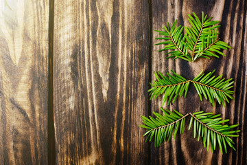 Spruce branches in the shape of fir tree on a wooden dark background. Happy New Year and Merry Christmas postcards.