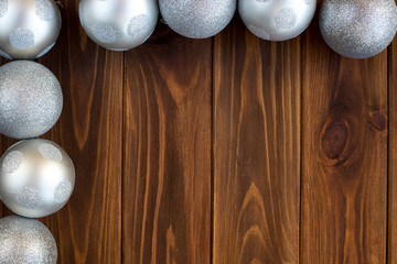 Christmas balls, toys on the Christmas tree silver on a brown wooden background
