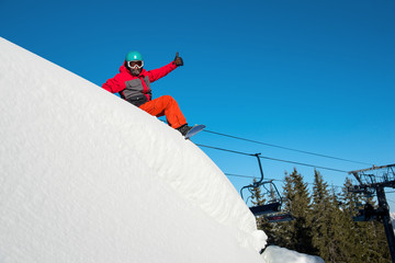 Shot of a happy snowboarder resting, sitting in the snow on top of the mountain at winter ski...
