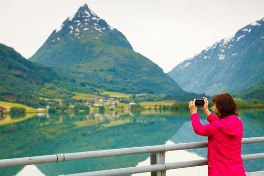 Tourist taking photo at norwegian fjord lake