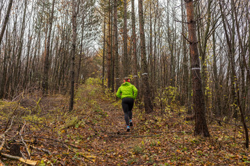 Fototapeta premium Girl in green dress running through a forest in autumn