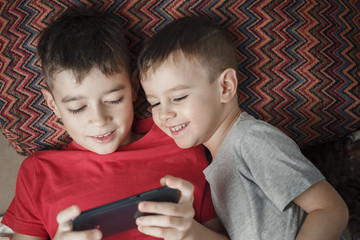 children lying down playing a cell phone