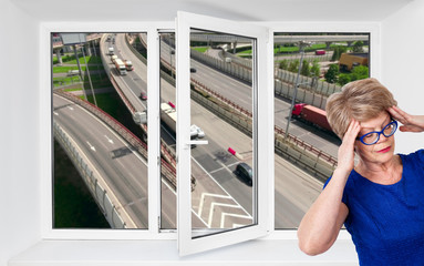 Opened triple-casement pvc window with noisy highway outdoor and senior woman with headache inside...