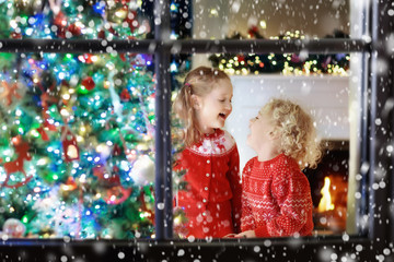 Fototapeta na wymiar Children at Christmas tree. Kids at fireplace on Xmas eve