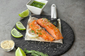 Slate plate with marinated slices of salmon fillet on table