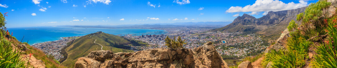 Fototapeta premium Panoramiczny widok na Kapsztad i Górę Stołową, a także pomoc sygnałowa zarejestrowana z Lions Head w ciągu dnia z błękitnym niebem z białymi chmurami, sfotografowana w RPA we wrześniu 2013 r.