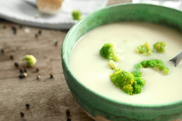 Bowl of yummy potato soup with broccoli on wooden table