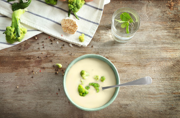 Bowl of yummy potato soup with broccoli on wooden table
