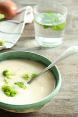 Bowl of yummy potato soup with broccoli on wooden table