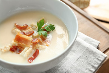 Bowl of yummy potato soup with bacon on wooden table