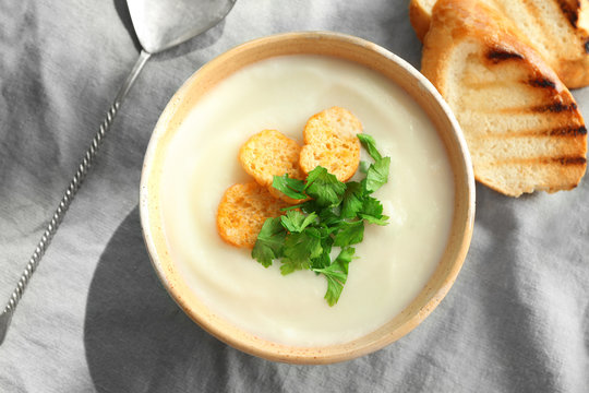 Bowl of yummy potato soup with croutons on table