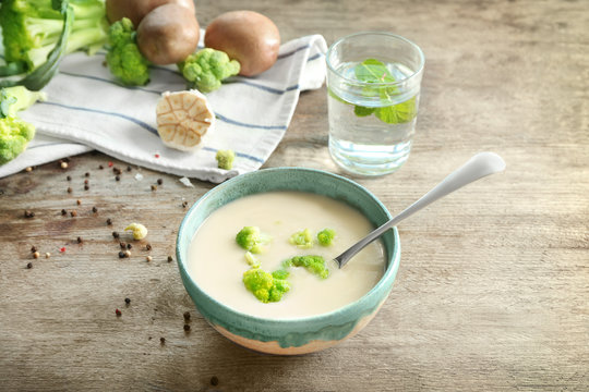 Bowl of yummy potato soup with broccoli on wooden table